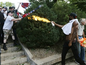 A counter demonstrator uses a lighted spray can against a white nationalist demonstrator at the entrance to Lee Park in Charlottesville, Va., Saturday, Aug. 12, 2017.