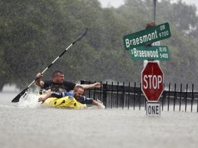 Two kayakers try to beat the current pushing them down an overflowing Brays Bayou from Tropical Storm Harvey in Houston, Texas, Sunday, Aug. 27, 2017. Hurricane Harvey brought as much as 50 inches of rain to America's fourth-largest city.