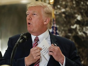 President Donald Trump reaches into his suit jacket to read a quote he made on Saturday regarding the events in Charlottesville, Va., as he speaks to the media in the lobby of Trump Tower in New York, Tuesday, Aug. 15, 2017.