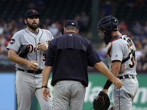 Detroit Tigers starting pitcher Michael Fulmer, left, talks with pitching coach Rich Dubee, center, and catcher James McCann, right, during a mound visit in the first inning of a baseball game against the Texas Rangers, Monday, Aug. 14, 2017, in Arlington, Texas. (AP Photo/Tony Gutierrez)