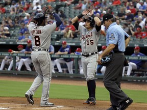 Detroit Tigers' Justin Upton (8) and Mikie Mahtook (15) celebrate Upton's two-run home run that scored them as umpire Angel Hernandez stands by the plate in the first inning of a baseball game against the Texas Rangers, Monday, Aug. 14, 2017, in Arlington, Texas. (AP Photo/Tony Gutierrez)