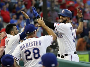 Texas Rangers' Robinson Chirinos, left, and manager Jeff Banister (28) congratulate Nomar Mazara on his two-run home run off of Detroit Tigers' Anibal Sanchez during the second inning of a baseball game, Wednesday, Aug. 16, 2017, in Arlington, Texas. (AP Photo/Tony Gutierrez)
