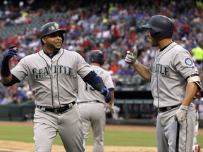 Seattle Mariners' Nelson Cruz, left, and Danny Valencia, right, celebrate a solo home run by Cruz during the second inning against the Texas Rangers in a baseball game Tuesday, Aug. 1, 2017, in Arlington, Texas. (AP Photo/Tony Gutierrez)