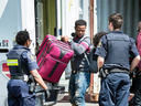 An asylum seeker unloads a suitcase from a truck at a processing centre near the Canada-United States border in Lacolle, Que., August 9, 2017.
