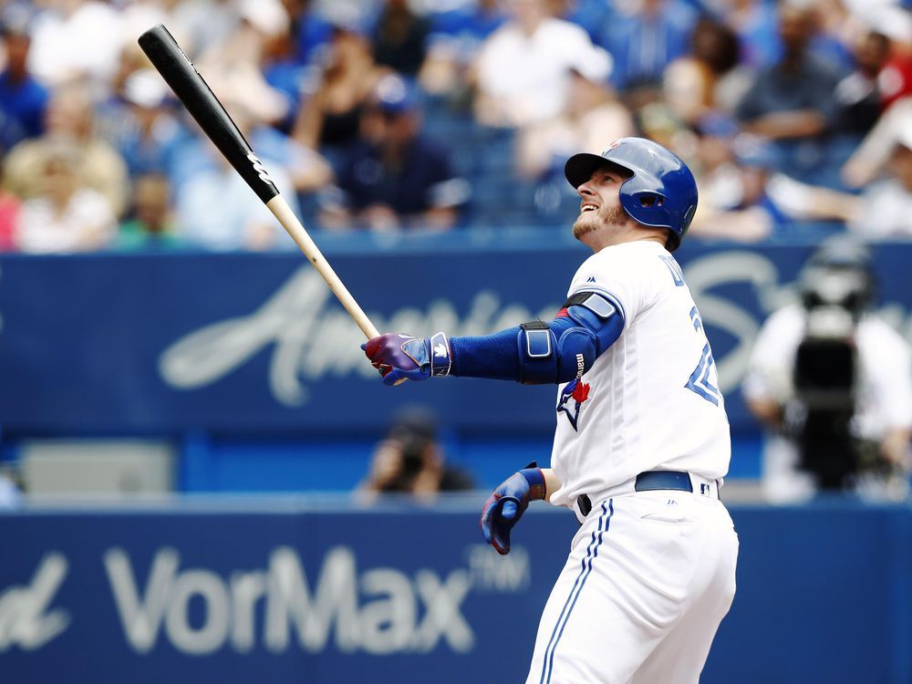 Josh Donaldson #20 of the Toronto Blue Jays puts on his helmet as he walks  back to third during a game …