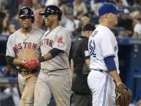 Rafael Devers, centre, and Xander Bogaerts of the Red Sox celebrate after scoring runs against Blue Jays pitcher Aaron Loup during the eighth inning of their  game in Toronto on Wednesday night.