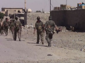 This frame grab from video released Friday, Aug. 11, 2017, and provided by Furat FM, a Syrian Kurdish activist-run media group, shows U.S.-backed Syrian Democratic Forces (SDF) fighters advance in Raqqa, Syria. U.S.-backed Syrian fighters advancing from eastern and western parts of the northern city of Raqqa have linked up for the first time in weeks after launching their offensive against Islamic State group fighters there. (Furat FM, via AP)
