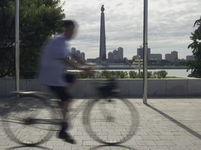 In this image made from video, a cyclist rides past as the Tower of Juche Idea monument can be seen at rear in Pyongyang, North Korea, Friday, Aug. 11, 2017. Despite tensions and talk of war, life on the streets of the North Korean capital Pyongyang remained calm. (AP Photo)