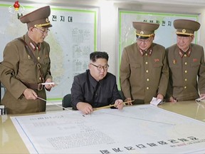 FILE - In this file image made from video of an Aug. 14, 2017, broadcast in a news bulletin by North Korea's KRT,  North Korean leader Kim Jong Un receives a military briefing in Pyongyang. Conventional wisdom says that if North Korea were ever to use its nuclear weapons, it would be an act of suicide. To many who have studied how nuclear strategies actually work, it's conceivable North Korea could escalate to a nuclear war and still survive. Tuesday's missile test suggests once again it may be racing to prepare itself to do just that _ but only if forced into a corner. (KRT via AP Video)