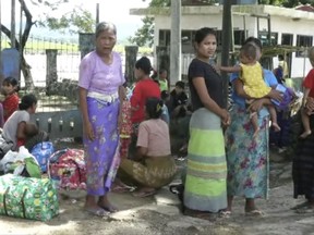 In this image made from video, residents displaced by violence wait in Buthidaung township, Sunday, Aug. 27, 2017, in Rakhine State, Myanmar. Myanmar's government and advocates for the country's Muslim Rohingya ethnic minority traded charges Sunday of killing civilians, burning down buildings and planting land mines, as clashes that began last week when insurgents launched attacks against police posts continued. (DVB via AP)