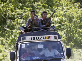 In this Monday, Aug. 28, 2017, file photo, Myanmar police guard from the roof of a truck carrying local U.N. staff fled from Maungdaw in Buthidaung, Rakhine State, western Myanmar. Armed with machetes and rifles, a ragtag band of insurgents comprised of members of Myanmar's Muslim Rohingya minority launched unprecedented attacks last week, triggering fighting with security forces that has left more than 100 people dead and forced at least 18,000 to flee into neighboring Bangladesh. (AP Photo, File)
