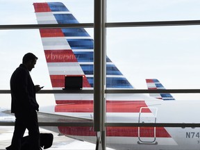 FILE - In this Jan. 25, 2016, file photo, a passenger talks on the phone as an American Airlines jets sit parked at their gates at Washington's Ronald Reagan National Airport. Ten people were injured last weekend as an American Airlines flight plowed through turbulence on its way to landing in Philadelphia. (AP Photo/Susan Walsh, File)