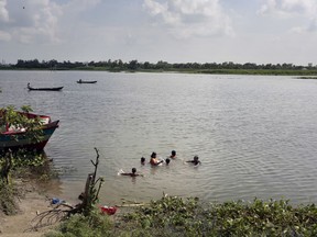 In this July 28, 2017 photo, Bangladeshi women and children take a bath in the river Burignaga in Noyadda village, Keraniganj, near Dhaka, Bangladesh. A British charity has partnered with a Bangladeshi research group to teach young children swimming as drowning is a major cause of deaths under 18 years old in the South Asian country. (AP Photo/A.M. Ahad)