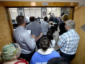 People overflow out of the council chamber as Councillor Denis Carr asks a question to Louis Dumas, director general of Immigration, Refugees and Citizenship Canada, right, during in a special meeting at Cornwall City Hall