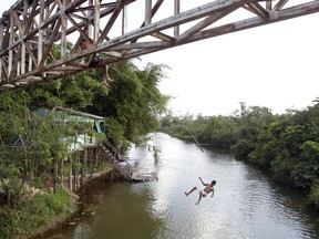In this Sept. 22, 2011 file photo, a youth jumps from an overpass into a river in Paragominas, northern state of Para, Brazil. A judge has halted a planned mining development in the ecologically sensitive and protected area.