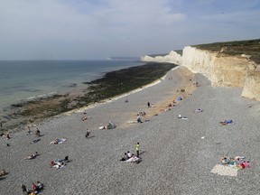 People relax on the beach at Birling Gap in Eastboune, Sussex, England, on Monday, Aug. 28, 2017. More than 100 people have been treated for streaming eyes, sore throats and breathing problems after a chemical haze spread over a stretch of southern England coastline.