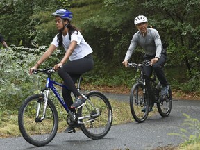 In this Aug. 22, 2015 file photo, U.S. President Barack Obama follows his daughter Malia as they rides bikes in West Tisbury, Mass., on Martha's Vineyard. The Obamas are taking their annual vacation on Martha's Vineyard as private citizens in August 2017, just weeks before Malia, is slated to start at Harvard.