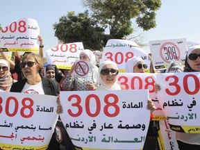 Women activists protest in front of Jordan's parliament in Amman with banners calling on legislators to repeal a provision that allows a rapist to escape punishment if he marries his victim.