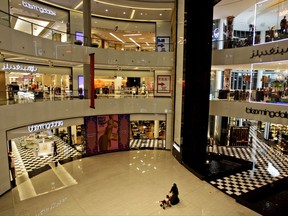 FILE - In this Aug. 3, 2011 file photo, an Emirati woman pushes a pram past Bloomingdales at a shopping mall in Dubai, United Arab Emirates. Friends and family say a transgender Singaporean and her friend have been sentenced to a year in prison in the capital of the United Arab Emirates for dressing in a feminine way. Friends and an advocacy group called Detained in Dubai say police stopped the two at Abu Dhabi's Yas Mall on Aug. 9, 2017 as they tried to eat at a food court. (AP Photo/Kamran Jebreili, File)