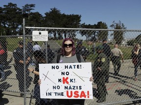 Andrea Smith holds up a sign in front of a fence blocking an entrance to Alamo Square Park in San Francisco, Saturday, Aug. 26, 2017.