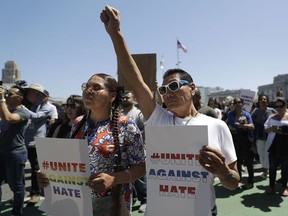 Jessica Heavy Runner, left, and her brother Eagle Tail hold signs at a rally in San Francisco, Friday, Aug. 25, 2017, ahead of politically conservative rallies scheduled  this weekend. Despite worries about violence at the upcoming free-speech rallies, some people plan to welcome their political opponents with unusual protests: a field of dog poop, red-nosed clowns and a giant inflatable chicken that bears the hairstyle of President Donald Trump. (AP Photo/Marcio Jose Sanchez)