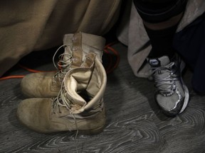 In this Monday, Aug. 14, 2017 photo, Iraq war veteran Vernon Poling, 44, sits on his bed next to a pair of combat boots he purchased right before his deployment in his apartment made out of shipping containers in Midway City, Calif. Poling, who had been medically discharged from the Army in 2014, was homeless for seven months. He was the last of 15 homeless veterans to move into Potter's Lane, American Family Housing's $6.7 million project. (AP Photo/Jae C. Hong)