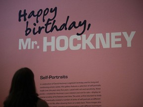 In this Wednesday, June 21, 2017 photo Alexandria Sivak, a senior communications specialist from J. Paul Getty Trust, reads a brief description of David Hockney's self-portraits in the exhibition hall at the Getty Center in Los Angeles. The aspiring artist was 17 when he took pencil to paper in 1954 and sketched out a stunningly mirror-like image of himself as a student at England's Bradford School of Art. In the 63 years since, David Hockney has become world famous not for self-portraits but colorful painted landscapes and brilliant photo collages of everything from backyard swimming pools to scenic desert vistas. (AP Photo/Jae C. Hong)