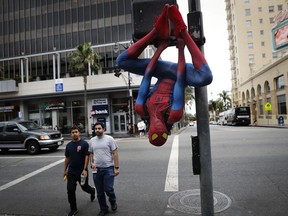 In this Thursday, May 25, 2017 photo, Rashad Rouse, 27, whose dream is getting his star on the Hollywood Walk of Fame, hangs upside down from a traffic signal pole in a Spider-Man costume to get attention from tourists on Hollywood Boulevard, in Los Angeles. Rouse is a musician and sometimes works as an Uber driver when he is not working on the boulevard. (AP Photo/Jae C. Hong)