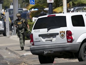 Law enforcement officers, including this Sacramento County sheriff's deputy surround a hotel where suspects believed to be involved in the shooting of police officers are located, Wednesday, Aug. 30, 2017, in Sacramento, Calif. (AP Photo/Rich Pedroncelli)