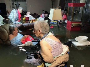 In this Sunday, Aug. 27, 2017, photo provided by Trudy Lampson, residents of the La Vita Bella nursing home in Dickinson, Texas, sit in waist-deep flood waters caused by Hurricane Harvey. Authorities said all the residents were safely evacuated from the facility. (Trudy Lampson via AP)