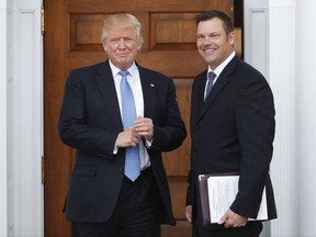 FILE - In this Nov. 20, 2016, file photo, Kansas Secretary of State Kris Kobach, right, holds a stack of papers as he meets with then President-elect Donald Trump at the Trump National Golf Club Bedminster clubhouse in Bedminster, N.J. Kobach, who is also vice chairman of Trump's Presidential Advisory Commission on Election Integrity, is seeking to avoid answering questions under oath about two documents containing plans for change U.S. election law. The closed deposition is scheduled for Thursday Aug. 3, 2017. (AP Photo/Carolyn Kaster, File)