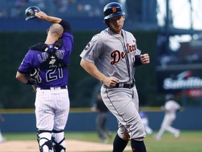 Detroit Tigers' Alex Presley, front, scores from third base on a double hit by Justin Upton as Colorado Rockies catcher Jonathan Lucroy, back, reacts in the first inning of a baseball game, Monday, Aug. 28, 2017, in Denver. (AP Photo/David Zalubowski)