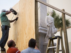 Workers place boards around a Confederate monument on Hillsborough County property in Tampa, Fla., Thursday, Aug. 17, 2017. In a divisive 4-2 vote Wednesday, Hillsborough County commissioners gave fundraisers 30 days to collect $140,000, about half of what's needed to relocate the monument from its spot in front of a courthouse annex in downtown Tampa.