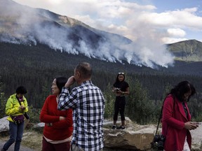 People gather on the side of the highway to watch a forest fire burn near Revelstoke B.C. on Saturday August 19, 2017. Restrictions on travel to British Columbia's backcountry and bans on campfires were lifted in some parts of the province on Wednesday as improved conditions lowered the wildfire risk. THE CANADIAN PRESS/Jason Franson