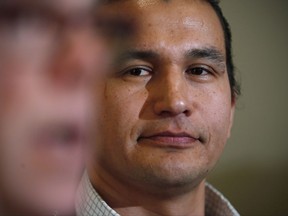 Wab Kinew, right, Manitoba NDP candidate for Fort Rouge, listens as Premier Greg Selinger responds at a news conference in Winnipeg, Friday, March 11, 2016. Wab Kinew says he wants to address what he says are lies and half-truths in the email that said he has been convicted of several crimes not previously reported. THE CANADIAN PRESS/John Woods