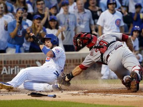 Chicago Cubs' Kris Bryant, left, scores past Cincinnati Reds catcher Devin Mesoraco off a double by Anthony Rizzo during the first inning of a baseball game Monday, Aug. 14, 2017, in Chicago. (AP Photo/Charles Rex Arbogast)