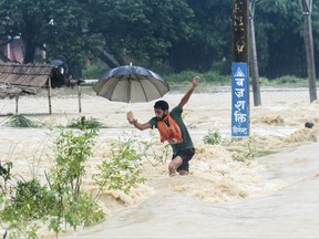 A Nepalese man looses his balance while crossing a flooded street in Birgunj, Nepal, Sunday, Aug. 13, 2017. An official said torrential rain, landslides and flooding have killed dozens of people in Nepal over the past three days, washing away hundreds of homes and damaging roads and bridges across the Himalayan country. (AP Photo/Manish Paudel)