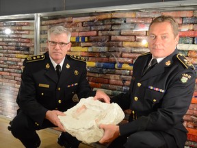 OPP Commissioner Vince Hawkes, left, and Deputy Commissioner Rick Barnum hold a hallowed out quartzite stone police say was used to smuggle cocaine into Canada from South America.