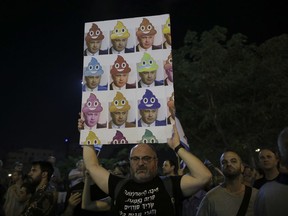 A man holds up a poster during a weekly protest against Israeli Prime Minister Benjamin Netanyahu, seen on the poster, in front of the home of Israel's attorney general Avichai Mandelblit in Petah Tikva.
