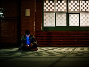 A refugee checks his cell phone at the prayer hall after arriving to Stockholm central mosque on October 15, 2015