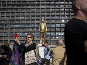 FILE - In this Tuesday, Dec. 6, 2016 file photo, people take pictures of a statue of Israeli Prime Minister Benjamin Netanyahu at a central square in Tel Aviv, Israel. A series of scandals has left Netanyahu facing a growing grassroots protest movement that demands his indictment and removal from office. Weekly vigils in front of the home of Israel's attorney general now draw thousands of people, and the recent arrests of two vocal organizers have only further energized Netanyahu's opponents. (AP Photo/Oded Balilty, File)