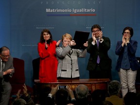 Chile's President Michelle Bachelet holds up a portfolio containing her signed proposal for a same-sex marriage bill at La Moneda presidential palace in Santiago, Chile, Monday, Aug. 28, 2017. (AP Photo/Esteban Felix)