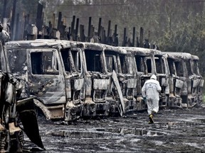 A police investigator walks past a row of charred trucks in San Jose de La Mariquina, in Chile's Los Rios region, Monday, Aug. 28, 2017. Hooded men burned several dozen trucks belonging to the privately owned Chilean company Sotraser SA. The attack occurred 800 kilometers, about 500 miles, south of Santiago, where groups of hooded men continually carry out violent actions mainly directed at large loggers in the area, a land that centuries ago belonged to the Mapuches, the native Indians of Chile. (Miguel Angel Bustos/Aton Chile via AP)