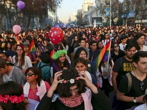 In this July 1, 2017 photo, Angela, below center, places a crown of flowers on her head as she attends a Gay Pride march alongside other transgender children in Santiago, Chile. The transgender children at the parade had socially transitioned to their chosen gender with the backing of their families. (AP Photo/Esteban Felix)