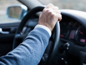 Man hand holding steering wheel in motion while drives.