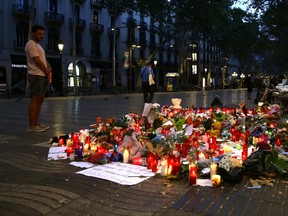 A man looks at flags, messages and candles placed after van attack that killed at least 13, in central Barcelona, Spain, Saturday, Aug. 19, 2017. Police on Friday shot and killed five people carrying bomb belts who were connected to the Barcelona van attack, as the manhunt intensified for the perpetrators of Europe's latest rampage claimed by the Islamic State group. (AP Photo/Manu Fernandez)