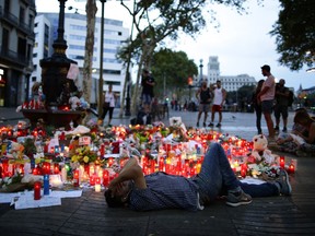 A man lays down next to messages and candles placed after a van attack that killed at least 13, in central Barcelona, Spain, Saturday, Aug. 19, 2017. Police on Friday shot and killed five people carrying bomb belts who were connected to the Barcelona van attack, as the manhunt intensified for the perpetrators of Europe's latest rampage claimed by the Islamic State group. (AP Photo/Manu Fernandez)