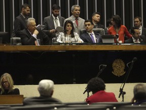 Deputy Mariana Carvalho, center, reads the report of the complaint against Brazil's President Michel Temer by the Committee on Constitution and Justice, during a session of the Chamber of Deputies, in Brasilia, Brazil, Tuesday, Aug. 1, 2017. President Temer faces a congressional vote on his future Wednesday, a showdown coming in a month dreaded by leaders of Latin America's largest nation. August has seen Brazilian presidents impeached, resign and even kill themselves. (AP Photo/Eraldo Peres)