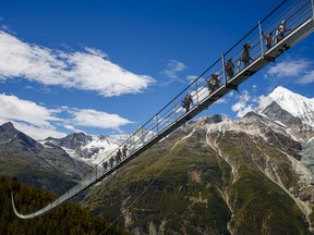 People walk on the "Europabruecke",  that is supposed to be the world's longest pedestrian suspension bridge with a length of 494m, after the official inauguration of the construction in Randa, Switzerland, on Saturday, July 29, 2017. The bridge is situated on the Europaweg that connects the villages of Zermatt and Graechen. (Valentin Flauraud/Keystone via AP)