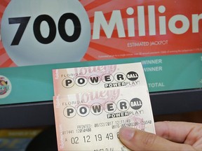 A customer shows her purchased Powerball tickets for Wednesday's drawing, Tuesday, Aug. 22, 2017, in Hialeah, Fla. The winner could take the $700 million annuity option (paid out over 29 years) or the $443.3 million cash prize, minus state and federal taxes. (AP Photo/Alan Diaz)